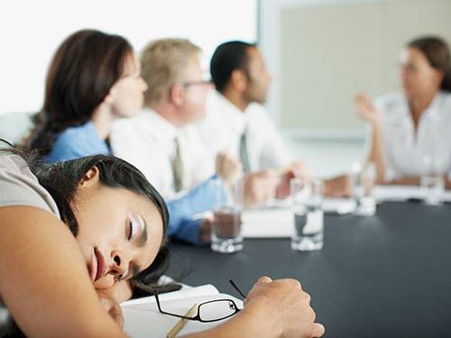 people sitting at a meeting with most engaged and one asleep